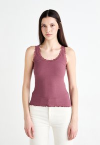 Canottiera a costine in mauve con pizzo lungo il colletto e le aperture delle braccia, caratterizzata da un design aderente e un orlo ondulato.