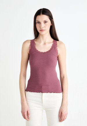 Ribbed tank top in mauve with lace trim along the neckline and armholes, featuring a fitted design and a wavy hem.