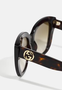 Gafas de sol de carey con montura sobredimensionada, lentes en degradado y un acento de logo dorado en la patilla. Acabado suave y brillante.