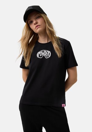 T-shirt en coton noir avec un graphique blanc de lunettes de ski et le texte "POWDER". Comprend une étiquette de marque rose à l'ourlet.