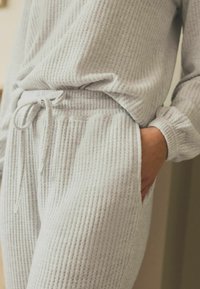 Helehall hallitusmaterjalist loungewear komplekt, millel on soonikkoeline tekstuur, elastne vöökoht, string ja küljetaskud.