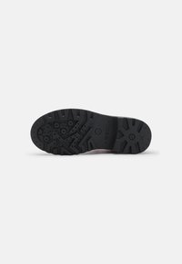Suela de zapato de goma negra con una suela texturizada que presenta un patrón de relieve único y detalles circulares para mejorar el agarre y la tracción.