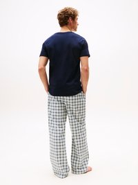 Navy short-sleeve top paired with loose, light plaid pajama pants featuring green and blue squares, designed for comfort.