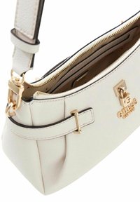 Sac à main en cuir blanc avec une fermeture éclair et des accessoires dorés. Présente un design structuré, une sangle plate et une petite plaque avec logo à l'avant.