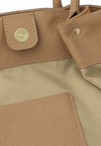 Beežikarva nahast käekott karestatud tekstuuriga, millel on kuldse tooniga metalldetailid ja beežist kangast vooder. Sealhulgas klõpskinnitusega sulgur ja taskud.