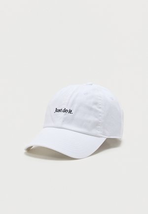 Bijela bejzbolska kapa s zakrivljenim vrhom i crnim izvezenim tekstom „Just do it.“ u sredini sprijeda na jednobojnoj pozadini.