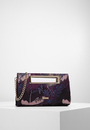 Lille rektangulær blomsterclutch i nuancer af lilla og pink med guldfarvet kæderem og udskåret håndtag på hvid overflade.