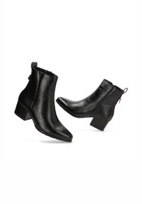 Botas de tobillo de cuero negro con punta afilada, tacón bajo tipo bloque y cierre de cremallera en la parte trasera. Textura suave con acentos de hardware mínimos.