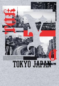 Camiseta con fondo gris, tipografía roja y negra prominente, y un collage de paisajes urbanos de Tokio en monocromo con características urbanas notables.