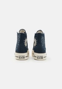 Zapatillas de lona altas azul marino con estampado de estrellas, suela de goma y detalles en blanco. Incluyen parche con el logotipo y costuras en contraste.