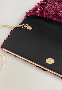 Hindbærfarvet pailletclutch med en solid sort inderside, guldhardware og en sikker trykknaplukning. Har en slank metallisk kæderyg.
