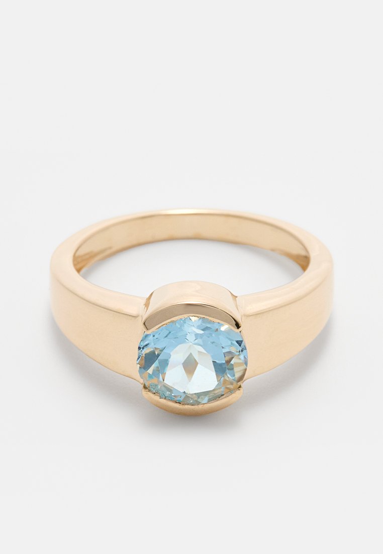 Goldring mit einem großen ovalen hellblauen Edelstein, der in einem glatten Band mit polierter Oberfläche eingesetzt ist. Das Design ist minimalistisch und modern.