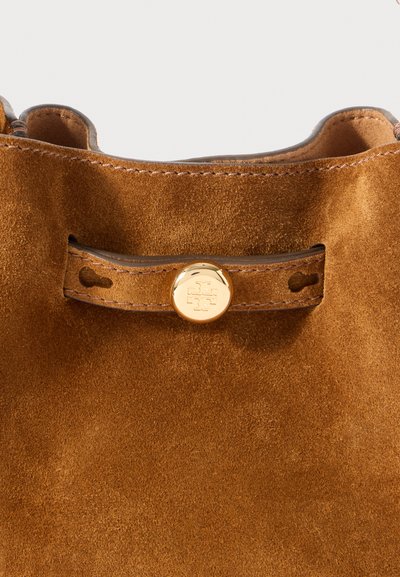 Brązowa torebka ze zamszu o zaokrąglonym dnie, z zapięciem na okrągły guzik w kolorze złotym i kontrastującymi szwami wzdłuż krawędzi.