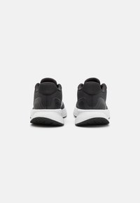 Black athletic shoes with a textured upper, round toe, and a white midsole. Heel features a smooth accent and a rubber outsole with grip.