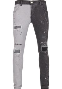 Denim jeans med et fargeblokkert design i grått og svart, med slitte lapper og sprøytet malingsdetaljer.