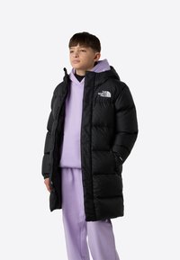 Must puffer-jakk kapuutsiga, tõmblukk ja The North Face'i logo rinnal, kantud üle helelilla kapuutsiga dressipluusi ja sobivate pükste.