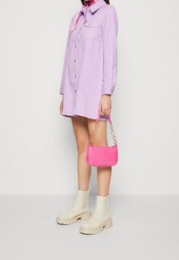 Lilahe Button-Down Shirtkleid, rosa handtasche mit Krokodil-Prägung und Kettenriemen, beigefarbene Stiefeletten mit dicker Absätzen und ein gemustertes Tuch.