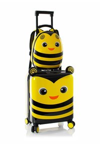 Valigia a rotelle a tema ape, gialla e nera, con un volto sorridente, progettata con strisce, occhi tondi e dettagli accentuati su orecchie e manico.
