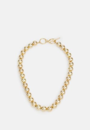 Złocony metaliczny naszyjnik z okrągłymi koralikami i zapięciem typu toggle na jednolitym białym tle.
