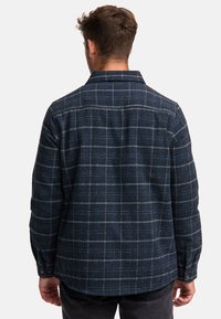 Navy blue checkered flannel shirt featuring a collar, long sleeves, button cuffs, and a relaxed fit with a textured woven pattern.