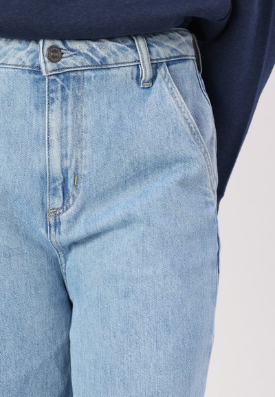 Jean en denim bleu clair à taille haute, avec une fermeture à bouton et à zip à l'avant, et un design classique à cinq poches. Texture lisse.