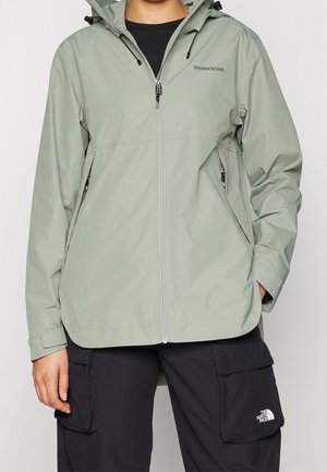 Veste imperméable vert clair avec fermeture éclair à l'avant, capuche ajustable et poches latérales. Présente un logo distinctif sur la poitrine et les poignets.