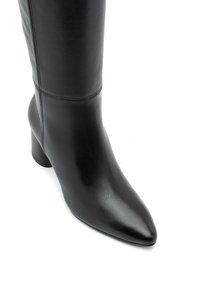 Bota de cuero negro hasta la rodilla con punta afilada y tacón bloque de altura media. Presenta una textura suave y un detalle de costura mínima.