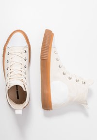 Höga canvas-sneakers i off-white med gummisulor, med platta snören, metallöglor och en subtil mönstrad detalj.
