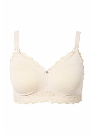 Sujetador inalámbrico de color beige suave con tirantes ajustables, ribete de encaje en los bordes superiores y la banda inferior, y un pequeño lazo decorativo con un botón en el centro.