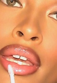 Gloss transparent appliqué sur des lèvres pleines et brillantes, mettant en valeur une teinte rose pâle. Gros plan mettant en évidence une texture lisse et un éclat subtil.