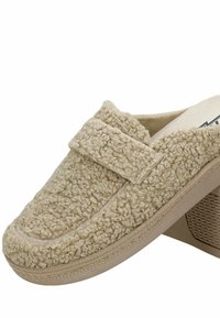 Beige women's loafer with curly textured fabric upper, rounded toe, and low wedge heel with patterned rubber sole.