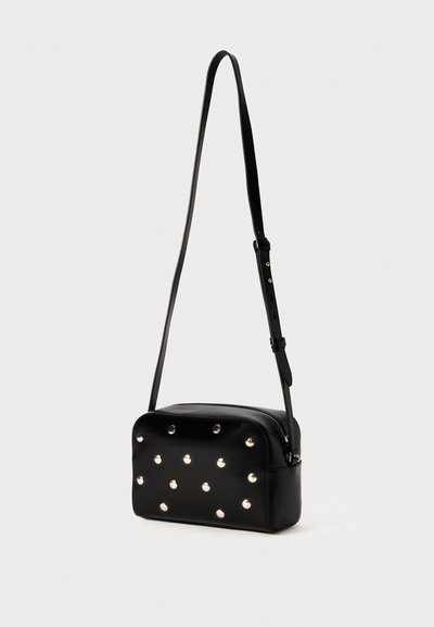 Černá kožená crossbody taška s hroty, obdélníkový tvar, nastavitelné rameno a zipové zapínání, s hladkým povrchem.