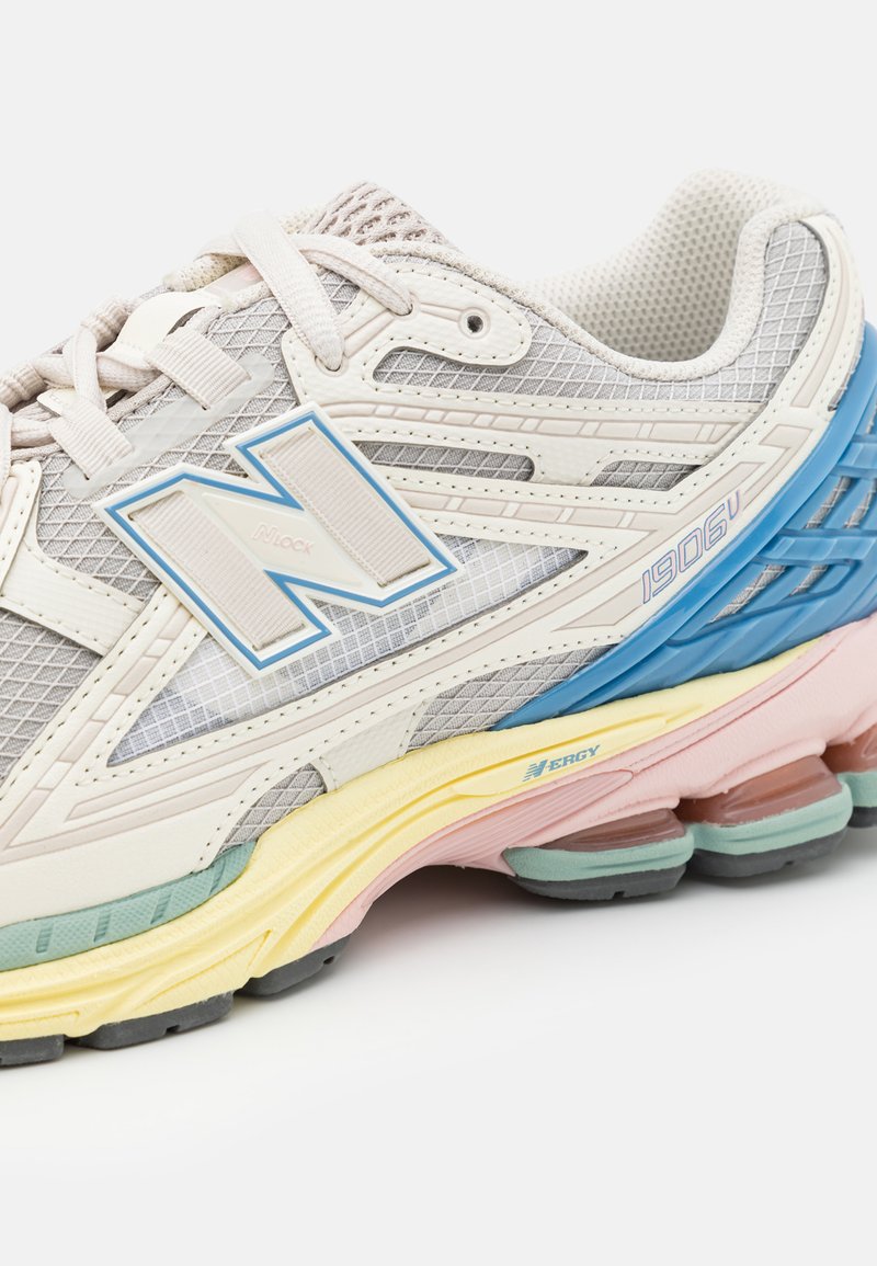 Zapatilla de correr de malla blanca y gris con acentos en azul, rosa y verde; cuenta con detalles reflectantes y una suela acolchada para mayor comodidad.