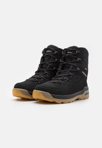Schwarze Wanderschuhe mit einem strukturierten Obermaterial, gepolstertem Kragen, schwarzen Schnürsenkeln und einer Gummisohle mit Honigwabenmuster.
