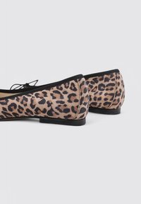 Bailarinas de estampado de leopardo con un upper de ante texturizado, ribete negro y un tacón bajo y sólido. Presentan un detalle de lazo de cordones en la parte delantera.