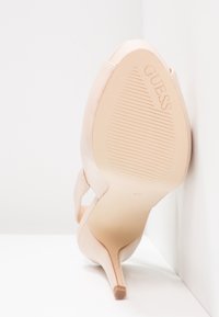 Scarpa con tacco alto rosa con finitura in vernice liscia; punta affusolata; tacco sottile; suola rigata; nome del marchio impresso sul fondo.