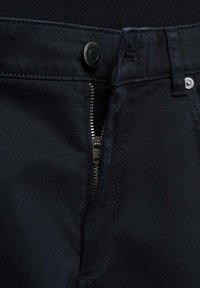 Dark blue jeans with a metal zipper at the front, a metal button closure, and stitched details, showcasing a sleek design and smooth texture.