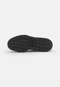 Svart sneaker såle med teksturert mønster, med diamantformer og spor for grep. Gummi materiale med flat design.