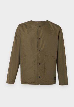 Olívazöld hosszú ujjú dzseki kerek nyakkal, patentos záródással és két első foltzsebbel, fehér háttér előtt.