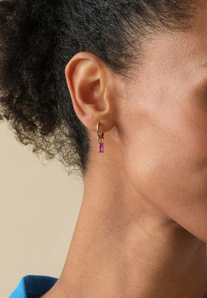 Goldene Creolen haben einen kleinen rosa rechteckigen Edelstein, der an einem Verschluss hängt. Das Design ist elegant und zeigt einen lebhaften Farbkonstrast.