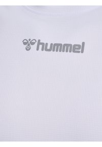 Vit sporttröja med strukturerad tygkvalitet. Har en ljusgrå "hummel"-logotyp framtill, centrerad med ett bi-emblem.