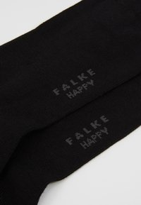 Schwarze Baumwollsocken mit glatter Textur; mit dem aufgedruckten "FALKE HAPPY" in hellgrauen Buchstaben an der Seite. Einfaches Design, Knöchelhöhe.