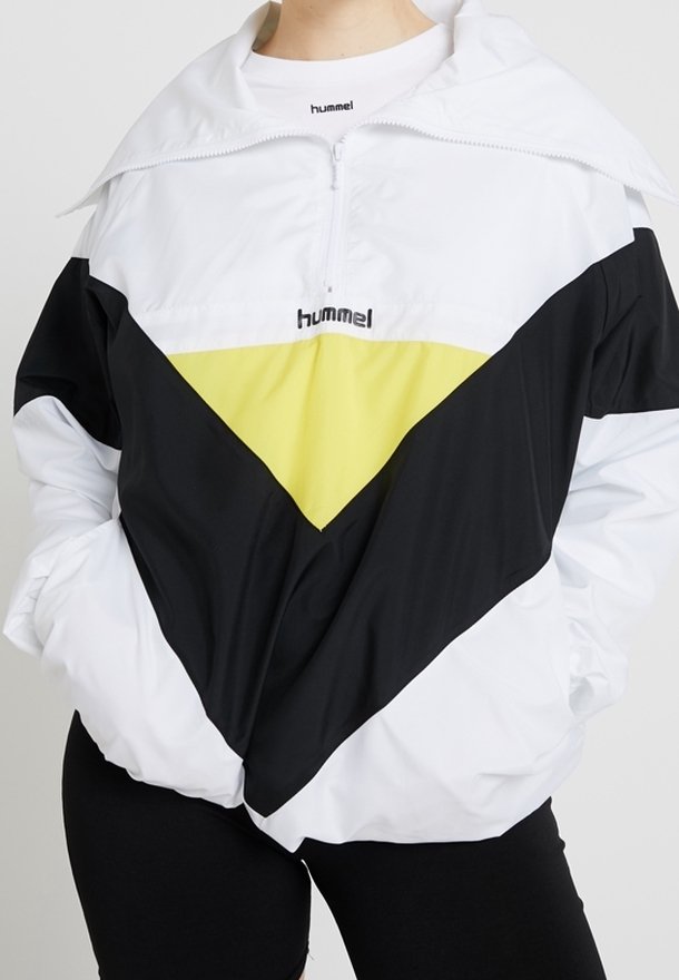 Biała, czarna i żółta kurtka wiatrówka z krótkim zamkiem, dużym kołnierzem, geometrycznym wzorem w blokach kolorów oraz logo Hummel na piersi.