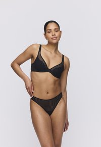 Mustat alusvaatteet, joissa on raidoitettu muotoilu. Rintaliivissä on toppaus ja leveät olkaimet; alushousut ovat matalavyötäröiset ja niissä on sama kuosi.