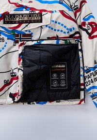 Bunte Innenausstattung einer Daunenjacke mit abstrakten Mustern in Rot, Blau und Grün. Verfügt über ein schwarzes Futter und ein Pflegeetikett mit Symbolen.