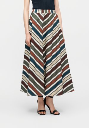 Femme portant une jupe trapèze taille haute à rayures multicolores, des sandales à talons noires et un haut sans manches noir.