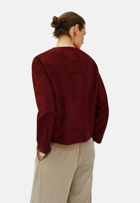 Mjukt maroonfärgat mockajacka med avslappnad passform, rundad halsringning och långa ärmar. Texturerad yta med en ren sömdetalj bak.