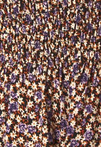 Květinová textilie s našívaným vzorem, na černém pozadí s fialovými, oranžovými a bílými květy. Texturovaný povrch a sklady.