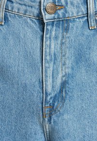 Lyseblå denimjeans med høy midje-design, utstyrt med en metallknapp og kontrastfarget oransje søm langs sømmene.