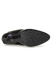 Zapato de tacón negro con parte superior de cuero liso y un panel de ante texturizado. La suela presenta letras grabadas y un tacón rectangular.